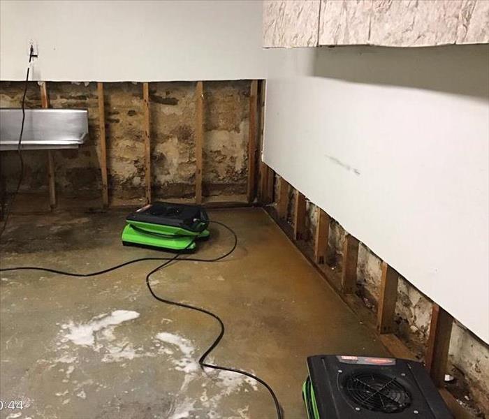 Flood cuts, wet flooring, and drying equipment in a basement.